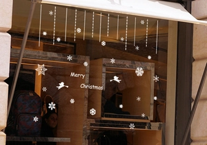 White Christmas window stickers with snowflakes and flying angels on a glass storefront