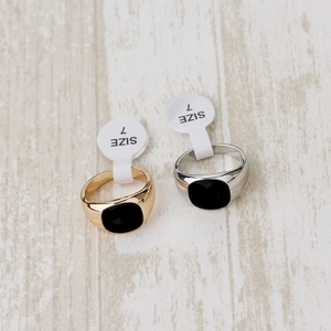 Detailed top view of gold and silver signet rings with black enamel and size 7 tags