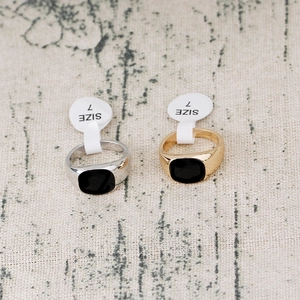 Macro shot of silver and gold rings with square black stones on a beige linen surface