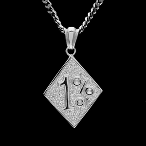 Macro shot of silver diamond-shaped 1%er pendant with textured relief and cuban chain