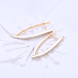 Elegant gold-plated elongated curved earrings with shimmering zircon stones on white background