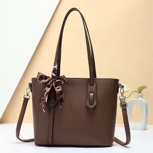 Detailed macro view of brown pebbled leather tote bag with silk scarf accessory and strap