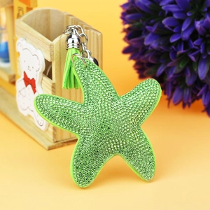 Close-up of green starfish keychain with rhinestones, leather tassel and bell charm