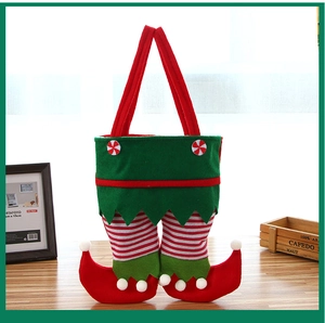 Detailed view of Christmas elf leg gift bag with red and green stripes on wooden surface