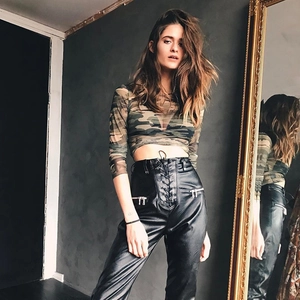 Women camouflage long sleeve mesh top paired with high-waisted black lace-up leather pants