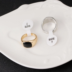 Polished 18K gold and silver signet rings with black gemstone inlay on textured ceramic