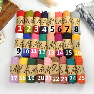 Macro view of 25 colored cotton linen scarves organized with kraft paper bands