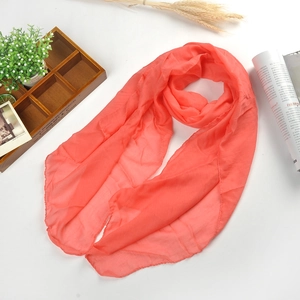 Coral pink linen blend scarf laid out on a white surface with natural wheat and wooden box