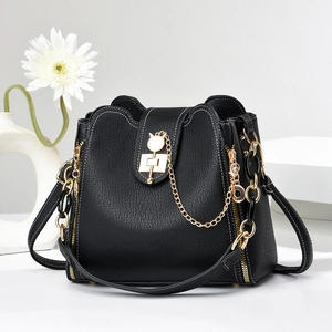 Détail du sac seau noir en cuir grainé avec fermoir à chaîne dorée et finitions métalliques