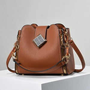 Detail der braunen Eimer-Tasche aus Leder mit Narbung und goldenem Metallverschluss
