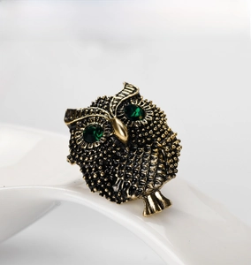 Detailed macro view of vintage owl brooch with emerald eyes and antique gold texture
