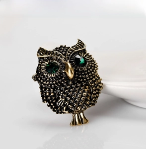 Detail of vintage owl brooch in antique gold finish with emerald green crystal eyes