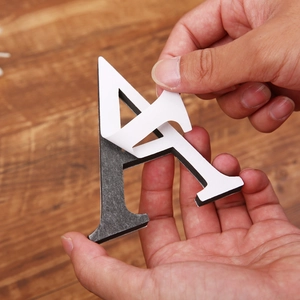 Detailed shot of peeling back adhesive film from a 3D black acrylic letter A wall sticker