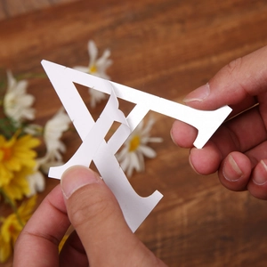 Detail showing hands peeling a white acrylic letter A wall sticker from its adhesive backing