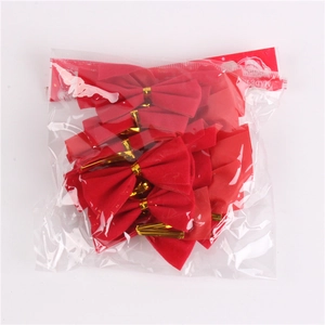 Close-up of mini red flocked Christmas bows with gold twist ties in plastic packaging