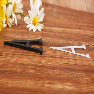 Detail showing high-quality black and white acrylic letters A on a dark wood background