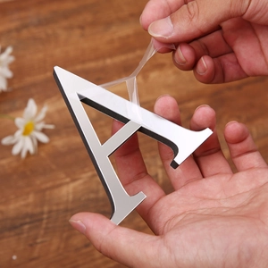 Close-up of light gold acrylic mirror letter A with protective film peeling away