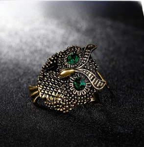 Detail shot of antique gold owl brooch featuring sparkling green crystal eyes