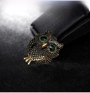Macro shot of owl brooch with antique gold plating and emerald green gemstone eyes