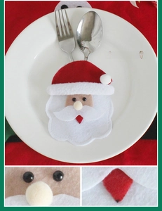 Detail of round-faced Santa Claus cutlery holder made of red felt fabric for Christmas