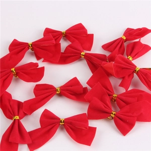 Close-up of small red flocked Christmas bows with gold twist ties on white background