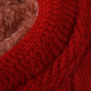 Dettaglio macro del berretto in maglia rossa con trama in pelliccia e fodera peluche