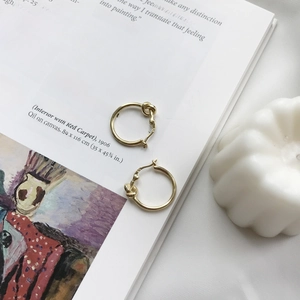 Detailed view of gold S925 sterling silver knotted hoop earrings with a metallic finish
