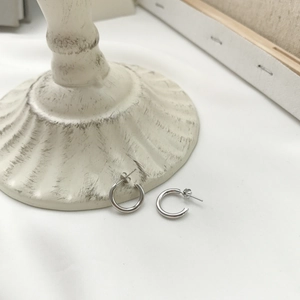 Detail of minimalist S925 sterling silver C-shaped geometric stud earrings on a white cloth