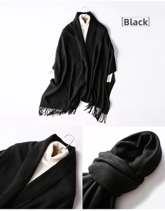 Detail view of black thick wool scarf with fringes and soft knitted texture on hanger