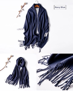Close-up of navy blue wool scarf featuring hand-knotted tassels and grey lining detail