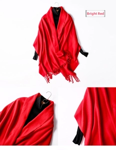 Detail view of red knitted wool shawl with fringes and soft fabric texture close-up