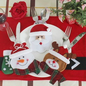 Christmas silverware holders featuring Santa, snowman, and reindeer shapes on festive dinner plates