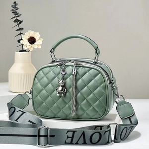 Close-up of Morandi green quilted crossbody bag with wide LOVE strap and bear charm
