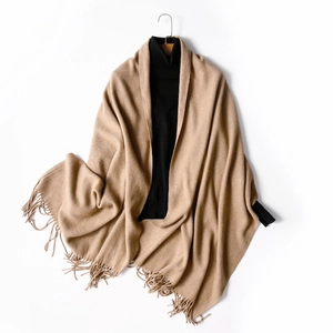 Classic khaki wool shawl with fringe tassels on a hanger with a black turtleneck sweater