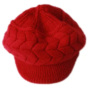 Dettaglio della spessa trama a trecce rosse e tesa del berretto in maglia