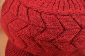 Dettaglio del cappello in maglia rosso scuro con trame a forma di V spesse e morbide