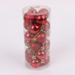 Detail of red Christmas baubles in matte and glitter finishes packed in a clear cylinder tube