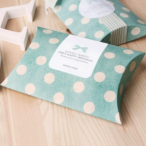 Détail de la boîte cadeau polochon vert menthe à pois avec étiquette bébé sur bois