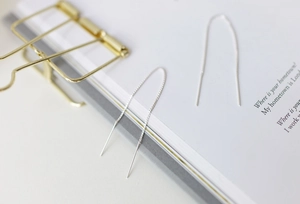 Detailed view of S925 sterling silver box chain earrings on a white book page
