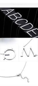 Detailed macro view of diamond-studded capital letter pendants on silver titanium steel chains