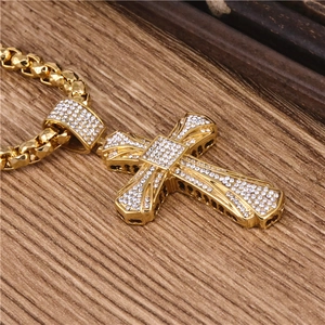 Polished gold cross pendant necklace with white crystals on vintage wood background