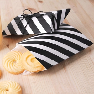 Detail of black and white striped paper pillow gift box with ribbon and cookies inside