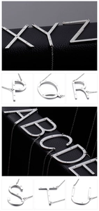 Polished silver alphabet pendants with crystals on black leather and white background