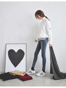 Full body view of a white high-neck sweatshirt with gray jeans and colorful scarves