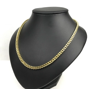 Close-up of golden Cuban link necklace on a black mannequin neck with studio lighting