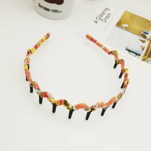 Close-up of orange printed fabric headband with black wavy base and fixing teeth