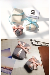 Close-up of elegant velvet jewelry boxes with silk ribbons in gray and beige tones