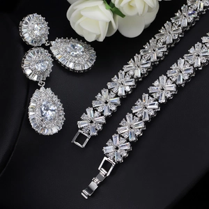 Macro detail of bridal teardrop earrings and floral zircon bracelet on black background