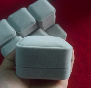Close-up of small square grey velvet jewelry box for rings and earrings in hand