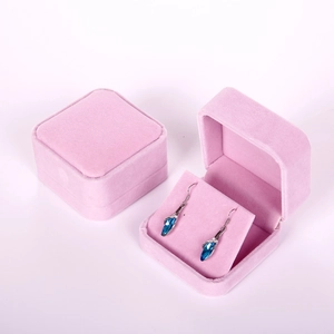 Close-up of pink velvet jewelry boxes showing teardrop earrings on a white background